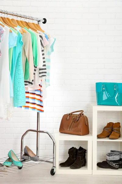 Vestiti diversi su grucce, scarpe su ripiani in negozio — Foto Stock