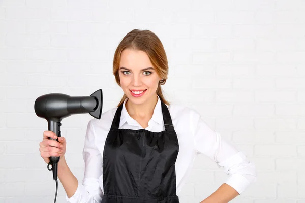 Beautiful girl hairdresser on light background — Stock Photo, Image