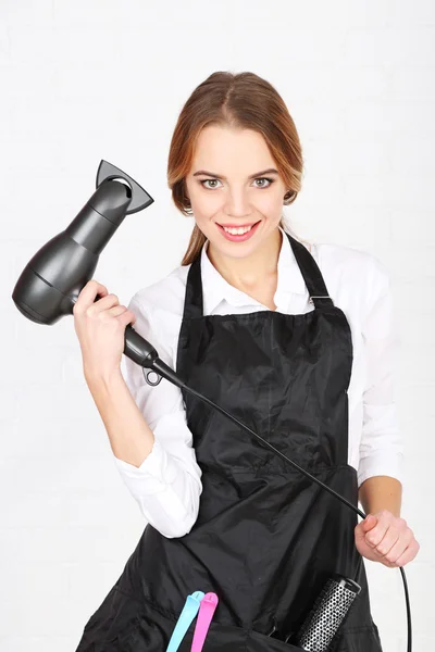 Beautiful girl hairdresser on light background — Stock Photo, Image