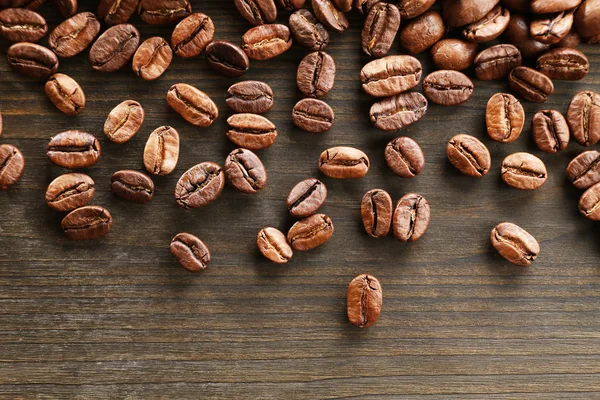 Grãos de café em fundo de madeira, close-up — Fotografia de Stock