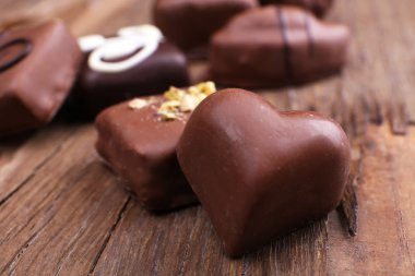 Tatlı şeker çikolata kalp ön plan ile ahşap dokulu arka plan üzerinde çeşitli