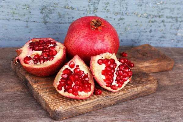 Juicy ripe pomegranates on old wooden table — Stock Photo, Image