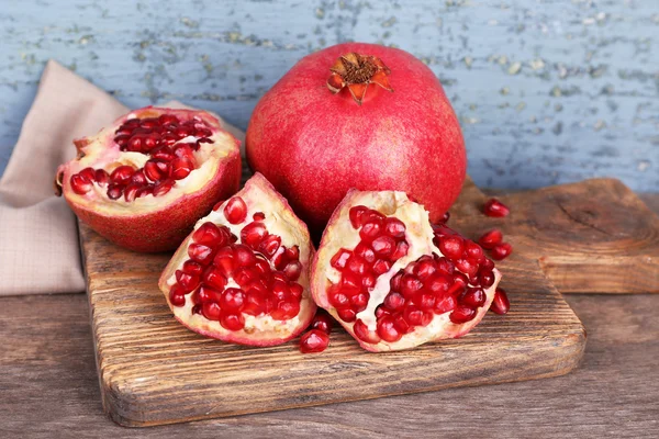 Juicy ripe pomegranates on old wooden table — Stock Photo, Image