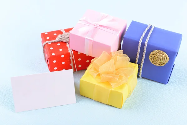 Colorful boxes with greeting card on blue uneven background — Stock Photo, Image