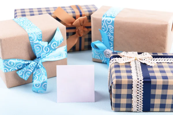 Gift boxes with greeting card on light blue uneven background — Stock Photo, Image