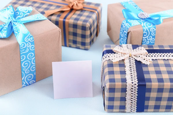 Cajas de regalo con tarjeta de felicitación sobre fondo irregular azul claro — Foto de Stock