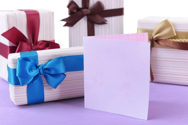 Симпатичные подарки с поздравительной открыткой на светло-голубой неровной поверхности, изолированной на белом — стоковое фото