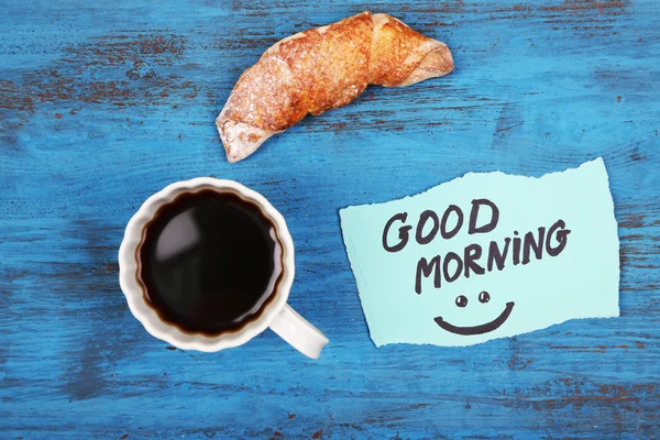 Samenstelling van koffie, verse croissants en papier kaart op houten achtergrond — Stockfoto