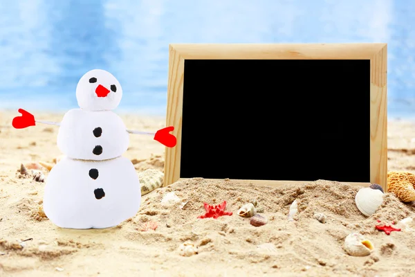 Christmas snowman op strand met het photoframe. — Stockfoto