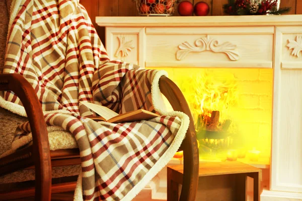 Rocking chair with plaid near fireplace — Stock Photo, Image