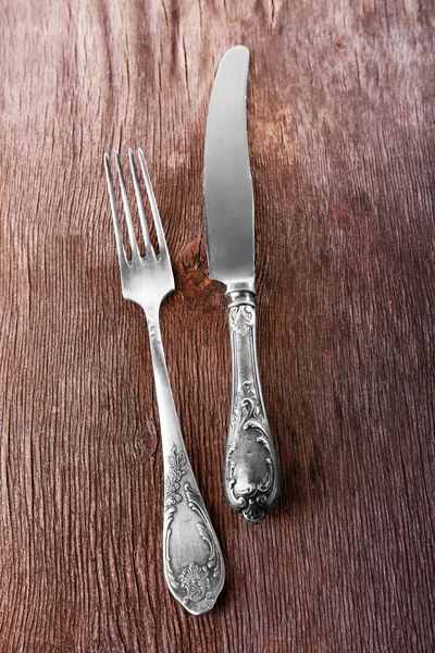 Mes en vork op houten ondergrond — Stockfoto