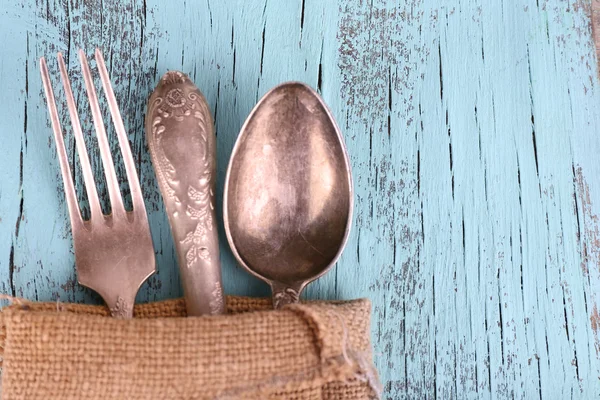 Tableware dibungkus dalam kain karung serbet pada latar belakang kayu biru — Stok Foto