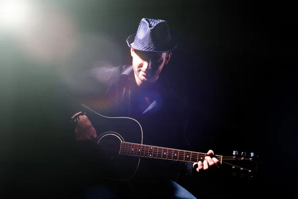 Junger Musiker spielt Akustikgitarre auf dunklem Hintergrund — Stockfoto