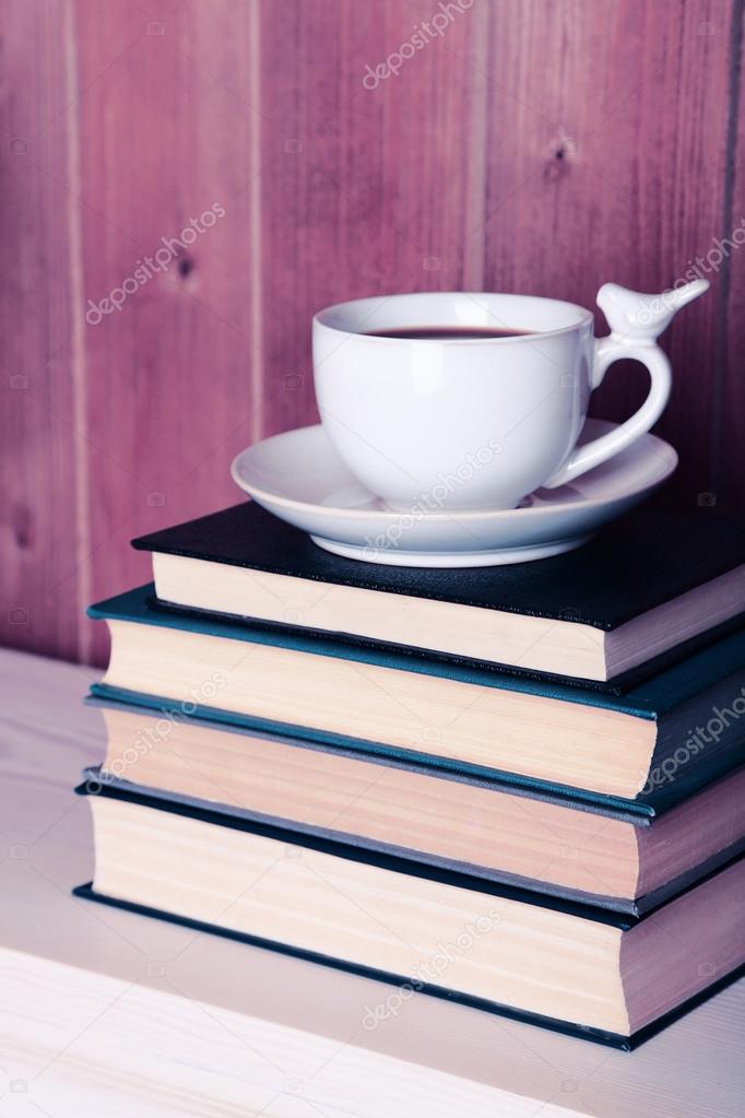 Old books and cup of coffee on table