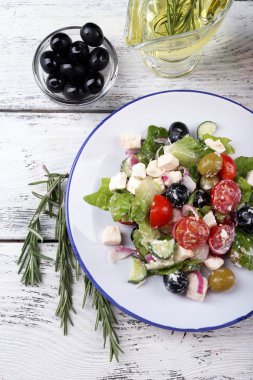 Yunan salatası ile zeytinyağı ve taze zeytin ahşap arka plan üzerinde servis tabak