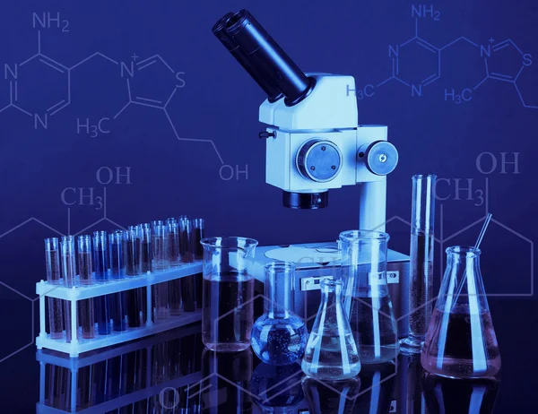 Test buizen met kleurrijke vloeistoffen en Microscoop op donkere achtergrond — Stockfoto