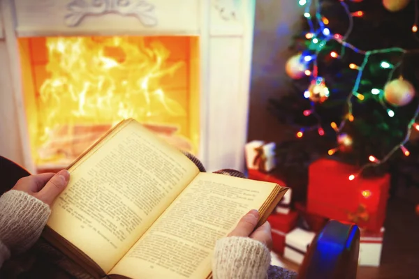 Mujer sosteniendo libro delante de la chimenea — Foto de Stock