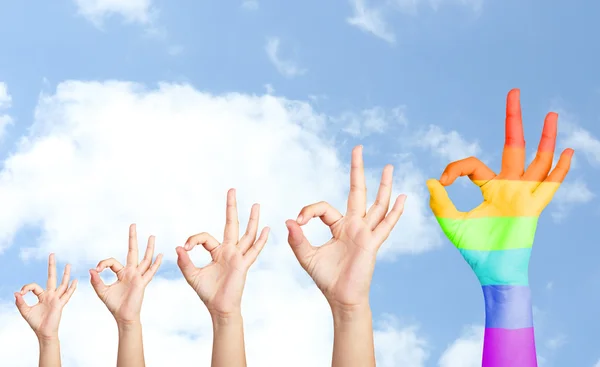 Las manos del hombre sobre el fondo del cielo, una mano pintada como bandera del arco iris —  Fotos de Stock