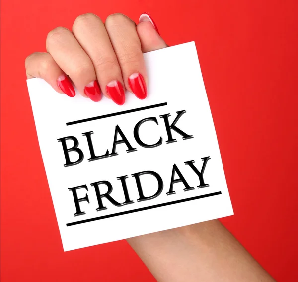 Woman's hand holding card with Black Friday text on red background — Stock Photo, Image