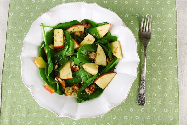 Salade verte aux épinards, pommes, noix et fromage sur fond de nappe de couleur — Photo