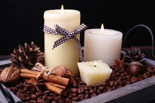 Candles on vintage tray with coffee grains and spices, bumps on wooden table, on dark background — Stock Photo, Image