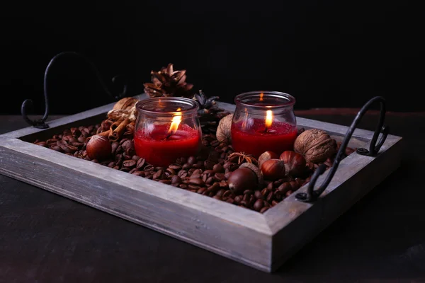 Candles on vintage tray with coffee grains and spices, bumps on wooden table, on dark background — Stock Photo, Image