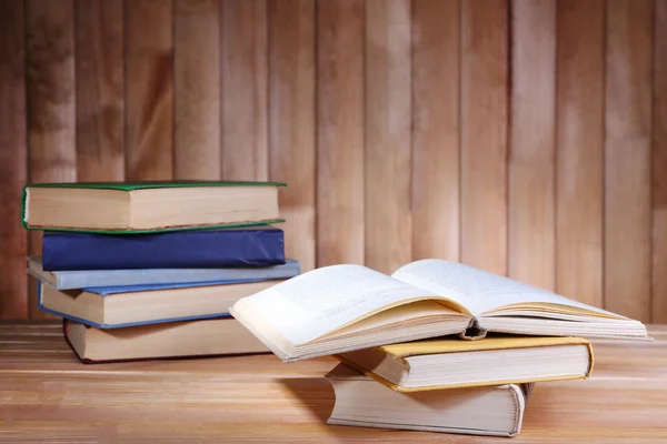 Libros sobre mesa de madera sobre fondo de pared de madera — Foto de Stock