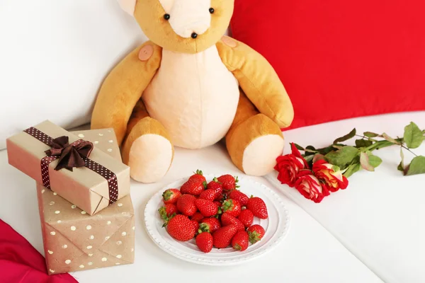 Romantic still life with gifts, strawberry and roses on sofa — Stock Photo, Image