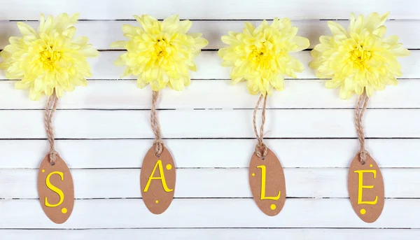 Belles fleurs de chrysanthème et étiquettes de vente sur fond blanc en bois — Photo