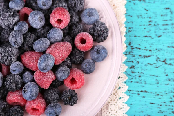 Iced berries on plate, on color wooden background — Stock Photo, Image