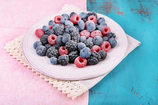 Iced berries on plate, on color wooden background — Stock Photo, Image