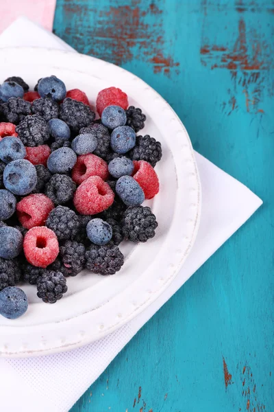 Iced berries on plate, on color wooden background — Stock Photo, Image