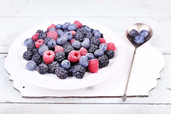 Baies glacées sur assiette, sur fond de bois couleur — Photo