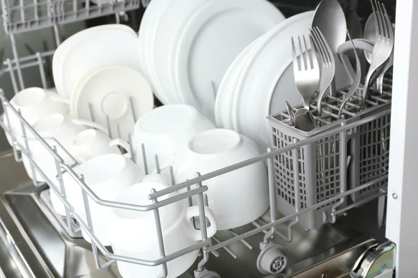 Открытая посудомоечная машина с чистой посудой в ней — стоковое фото