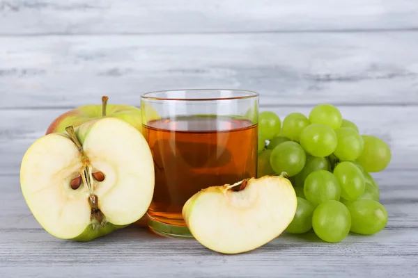 Glas sap met druivenmost en appels op grijze houten tafel — Stockfoto