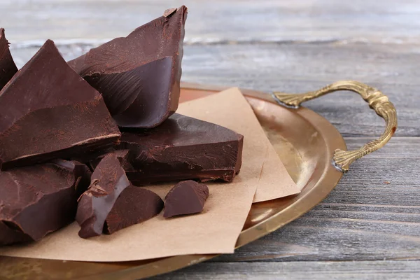 Cracked chocolate block on tray, on wooden background — Stock Photo, Image
