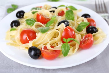 Tabak portre üzerinde spagetti domates, zeytin ve fesleğen yaprakları
