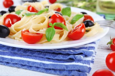 peçete ahşap zemin üzerinde plaka üzerinde spagetti domates, zeytin ve fesleğen yaprakları