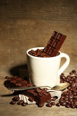 Fincan kahve çekirdekleri ve ahşap zemin üzerine koyu çikolata sır