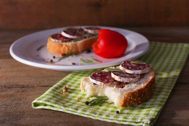 Sandviç salam plaka ve ahşap zemin üzerine peçete ile