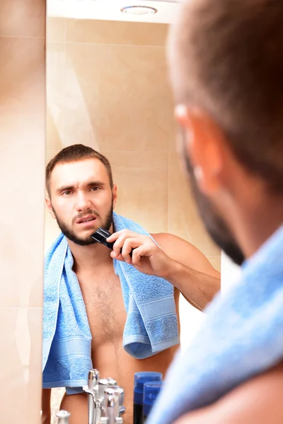 Young man shaving his beard in bathroom — Stock Photo, Image