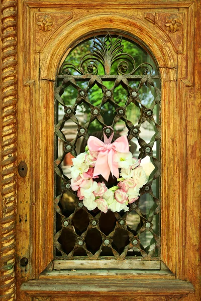 Beautiful wreath of flowers hanging on old wooden door — Stock Photo, Image