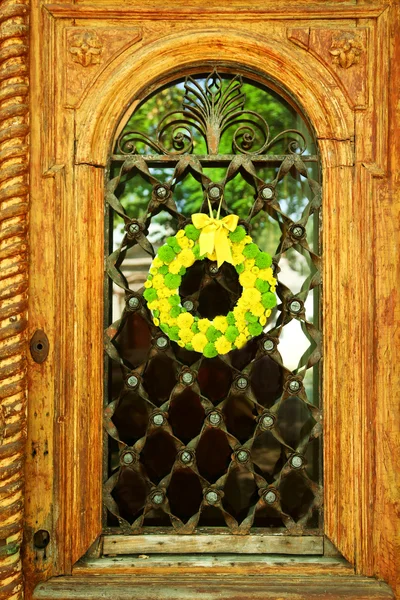 Piękny wieniec kwiaty wiszące na stare drewniane drzwi — Zdjęcie stockowe