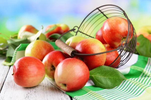 Sweet apples in wicker basket on table on bright background — Stock Photo, Image