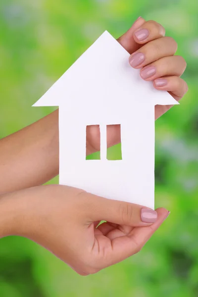 Donna mani tenendo casa di carta su sfondo luminoso — Foto Stock