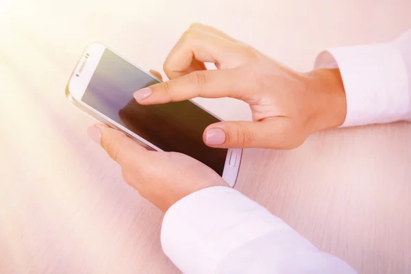 Frau benutzt Smartphone auf hellem Hintergrund — Stockfoto