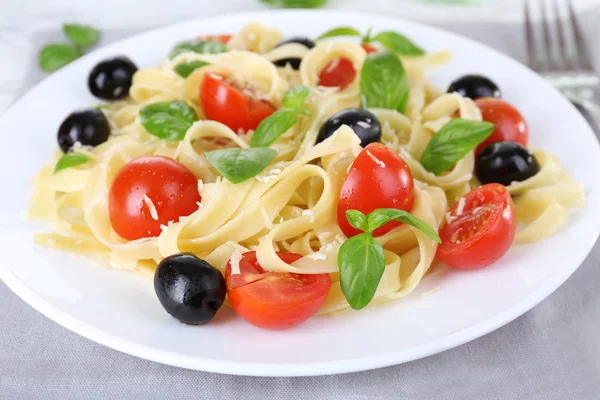 Espaguetis con tomates, aceitunas y hojas de albahaca en primer plano — Foto de Stock