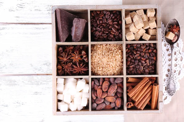 Kotak kayu dengan satu set kopi dan biji kakao, gula batu, cokelat gelap, kayu manis dan adas di atas latar belakang kayu — Stok Foto