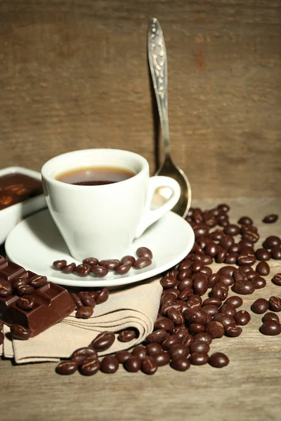 Cup of coffee and coffee beans with chocolate glaze on wooden background — Stock Photo, Image
