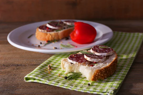 Sandwiches mit Salami auf Teller und Serviette auf Holzgrund — Stockfoto